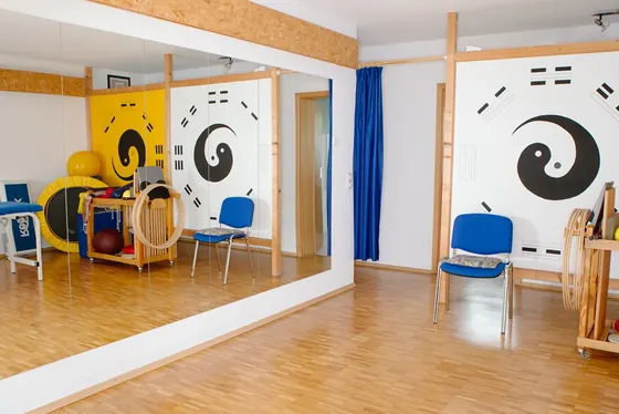 Bewegungsraum mit Yin-Yang-Wandbild, Stühlen und Spiegel